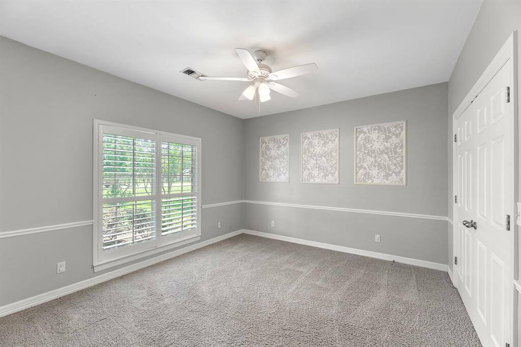 Located downstairs, this guest bedroom features elegant designer touches and a large window with plantation shutters that fills the room with abundant natural light.