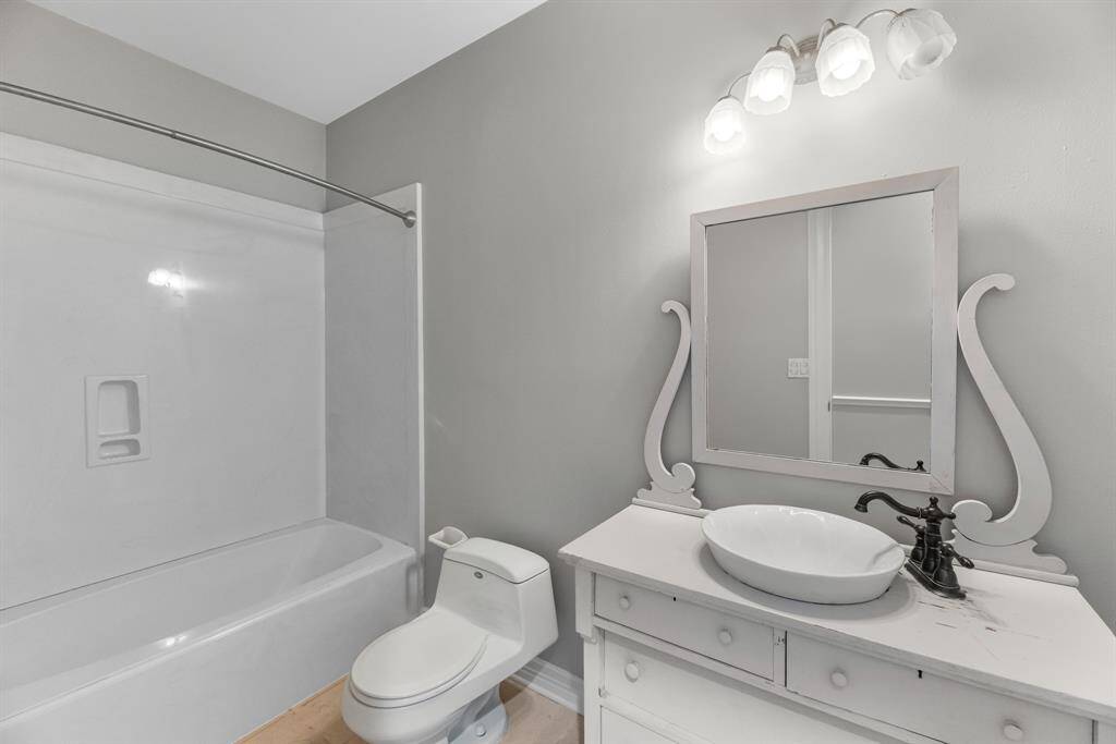 This full downstairs bathroom features a custom vanity with a stylish vessel sink and a convenient tub/shower combination, blending function and design seamlessly.