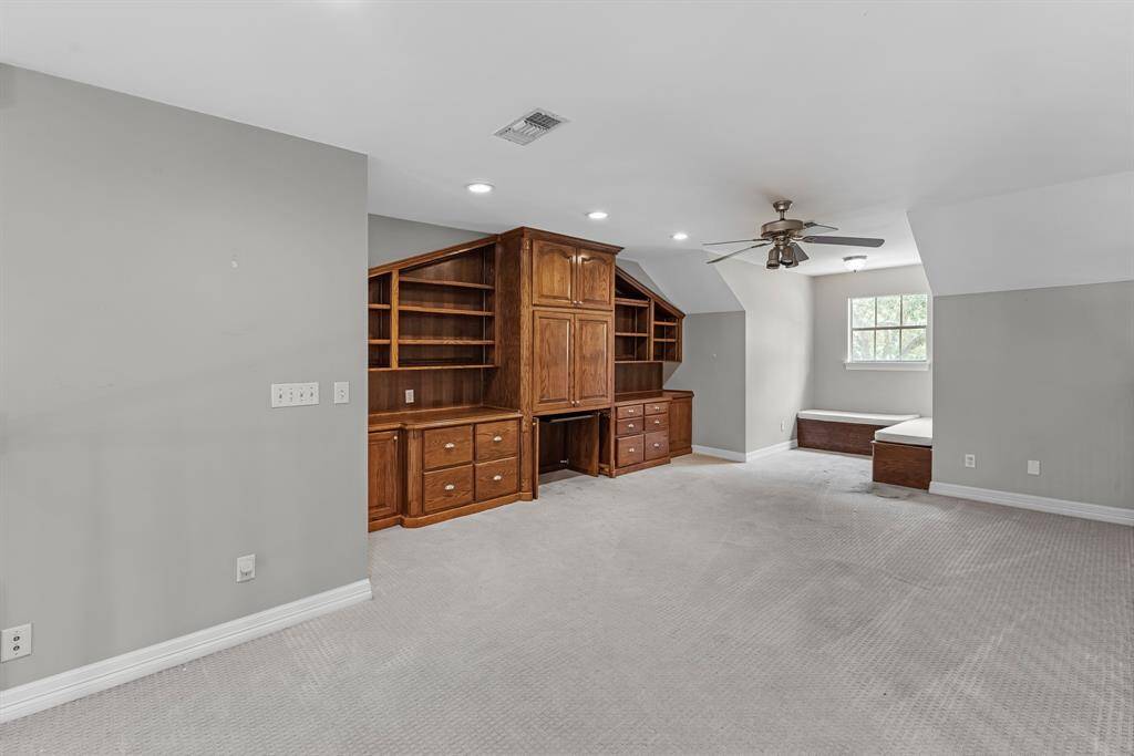 Upstairs, the spacious game room is full of character, featuring a custom built-in with cabinetry and drawers ideal for a home office. Cozy bench seating by the window and plush designer carpet complete this versatile space.