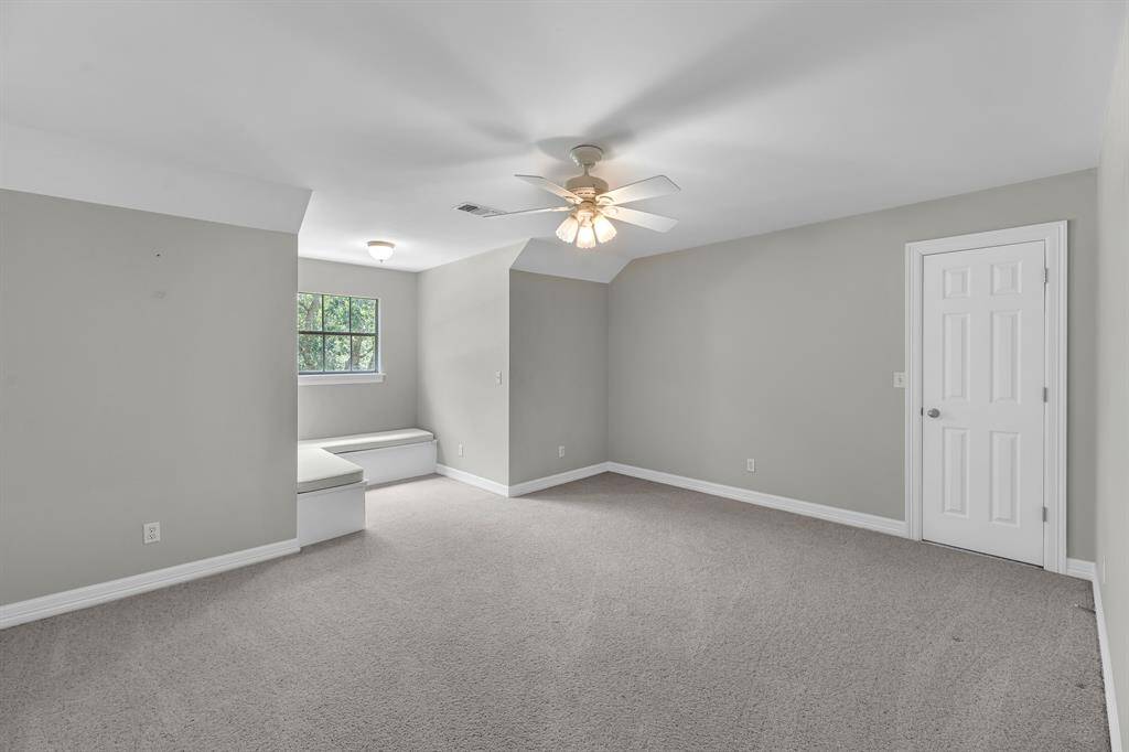 Upstairs, a spacious bedroom features plush carpeting, a ceiling fan, and a built-in window bench—creating a cozy and inviting retreat.
