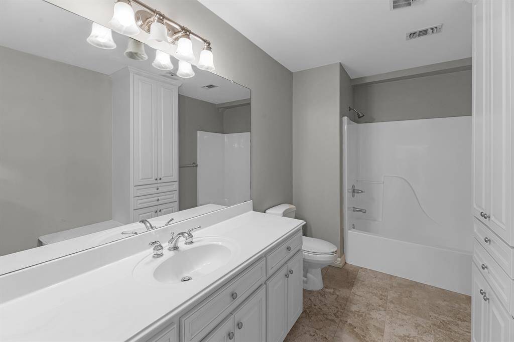 The upstairs full bathroom includes a large vanity with white countertops and cabinetry, nickel finishes, and a tub/shower combo framed by neutral tile flooring.