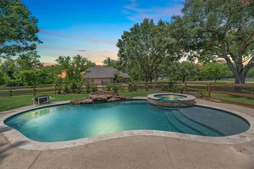 Enjoy stunning views of the sparkling pool and spa, featuring a generous sun shelf with steps, a soothing rock waterfall, and beautiful coping that adds elegant detail.