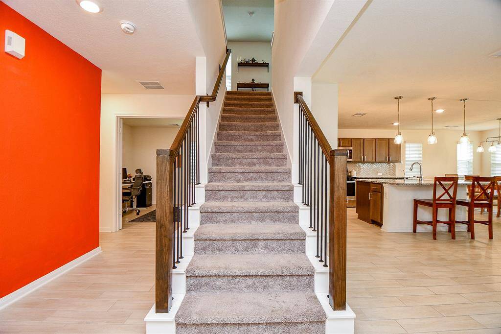 The staircase serves as a central visual feature downstairs, gracefully separating the tucked-away study on one side from the open living area on the other. This layout offers both connectivity and defined spaces for work and relaxation.