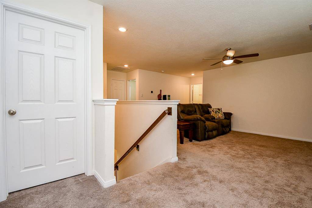At the top of the stairs, you’ll find a generously sized game room—perfect for family fun or relaxation. The utility room door is conveniently located here, making upstairs laundry easily accessible alongside the bedrooms.