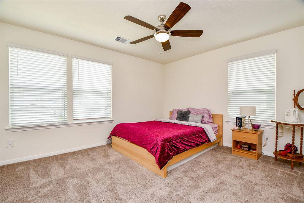 This large secondary bedroom features ample space and multiple windows that fill the room with natural light, creating a bright and inviting atmosphere.