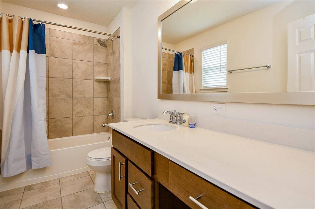 The secondary full bath is spacious and features a large vanity with ample counter space and convenient knee space for added comfort. The tub/shower combo is enhanced with a stylish tile surround, combining function and visual appeal.