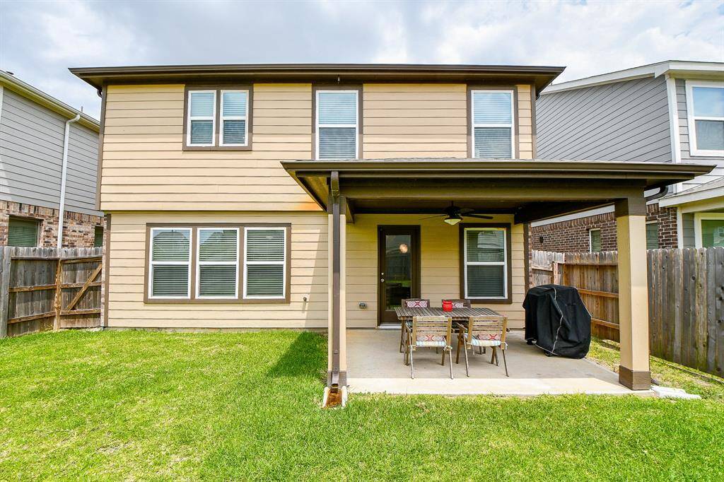 This view from the backyard highlights the covered patio and the inviting outdoor space it provides. Whether you're enjoying a quiet evening or hosting a weekend get-together, this patio is the perfect place to take in the spacious yard and relax in comfort.
