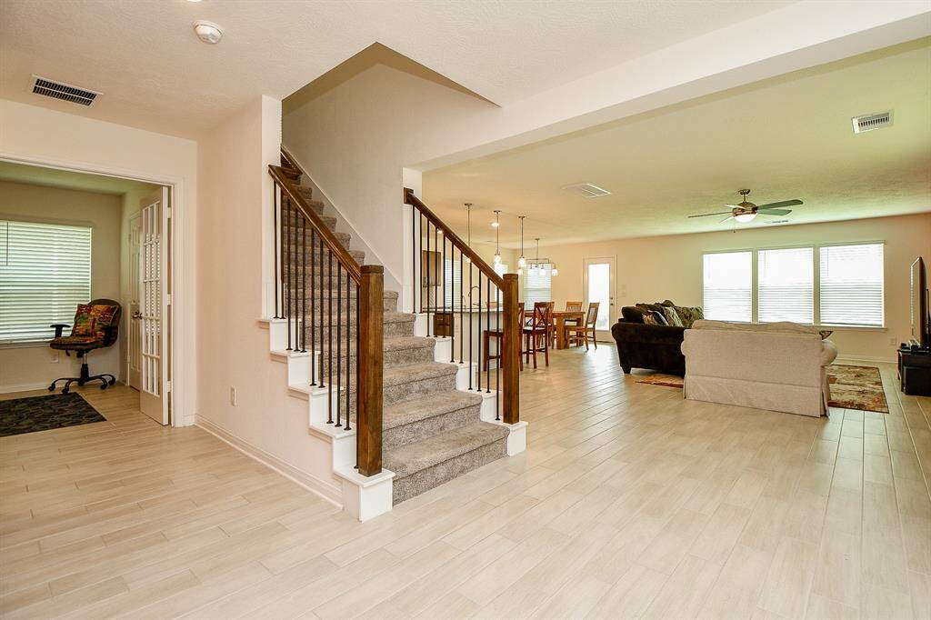 As you step inside, you're greeted by stylish tile plank flooring that sets a chic, modern tone. The open layout immediately draws your eye to the spacious living area and the staircase, creating a welcoming space that’s perfect for both relaxing and entertaining. To the left, a flexible downstairs room offers space for an office, playroom, or guest area. A conveniently located half bath adds to the home's functionality.