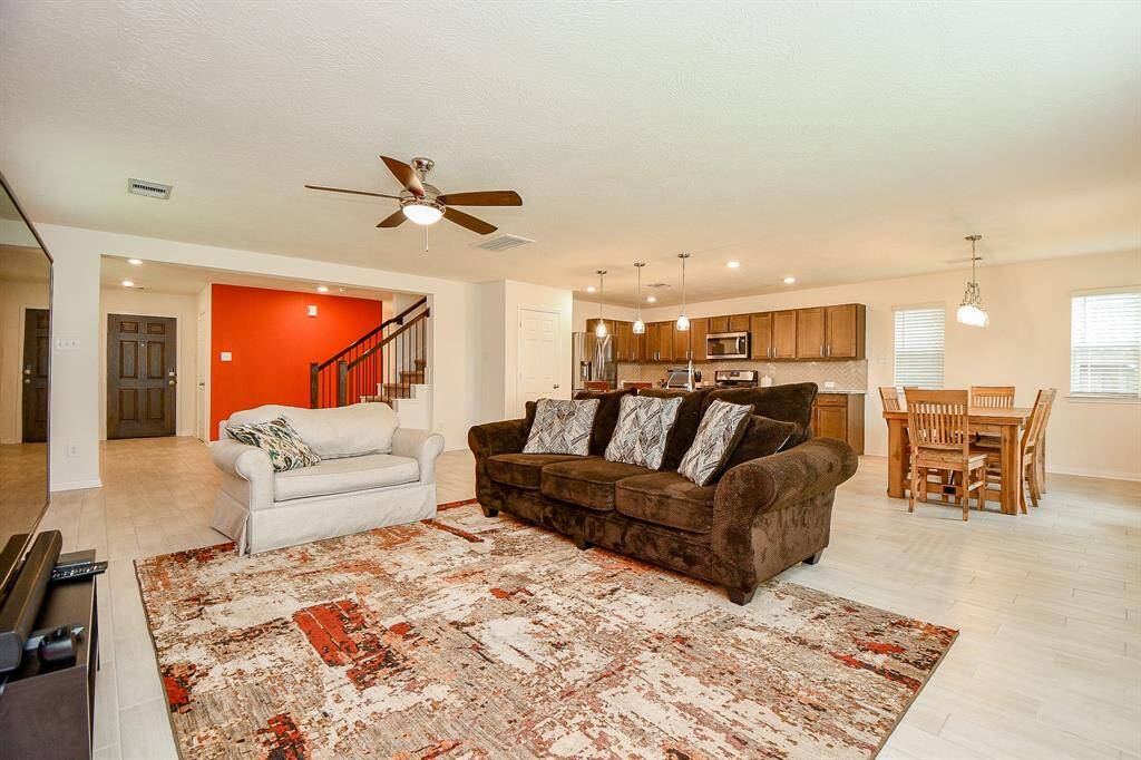 From this angle looking back toward the front door, you can truly appreciate the expansive flow of the downstairs. The huge open space, highlighted by tile plank flooring, creates a bright and airy atmosphere that’s perfect for both everyday living and entertaining.