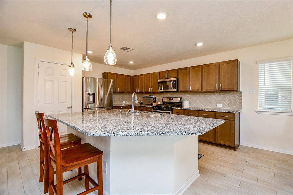 Here’s another view showcasing just how large the island is—offering plenty of space for meal prep and seating. The kitchen also includes a convenient walk-in pantry and a stainless steel refrigerator.