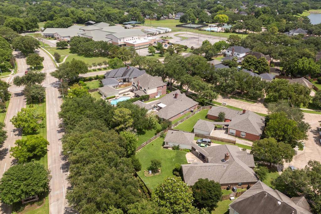 This aerial photo showcases a suburban neighborhood with well-maintained homes, tree-lined streets, and a nearby school. The area appears to be spacious and green, offering a peaceful residential environment.