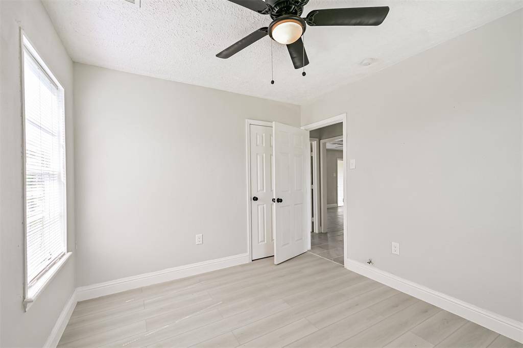 Secondary bedroom with sleek ceiling fan, soft neutral tones, and a view into the home's main areas—perfect for a guest room or home office.