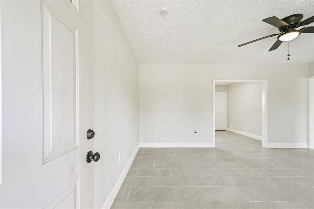 The front door leads you to the open and airy living room featuring clean tile floors, fresh paint, and a ceiling fan—move-in ready and full of potential.