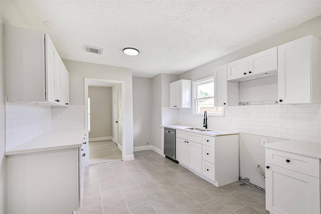 This bright and airy galley-style kitchen features updated white shaker cabinets, sleek black hardware, and ample counter space for cooking and prep.