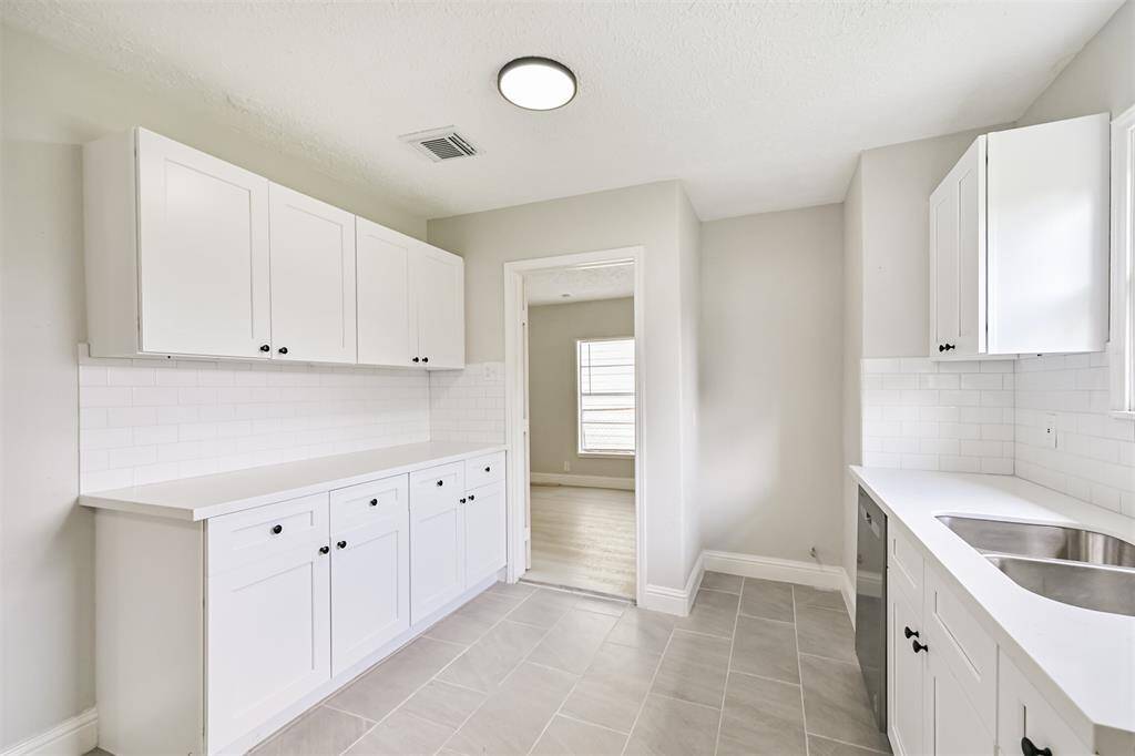 Boasting a spacious kitchen with soft gray tile flooring, full-height white subway tile backsplash, and crisp white quartz countertops—ready for your culinary adventures!