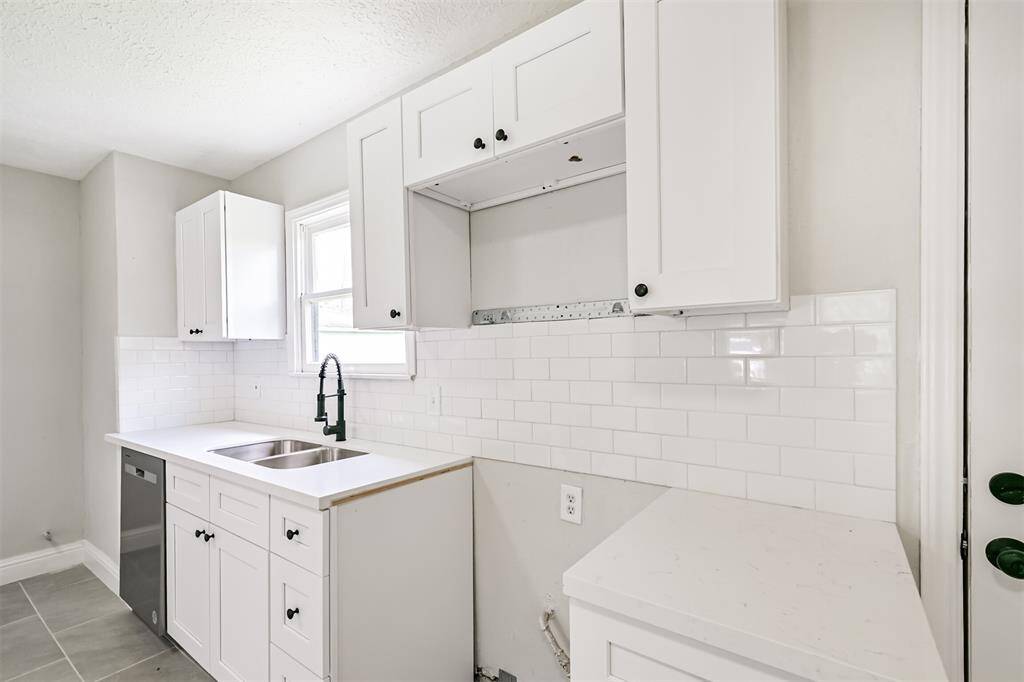 Modern subway tile backsplash, generous cabinet storage, sleek updated plumbing fixtures, and a designated space ready for your preferred oven or range installation.
