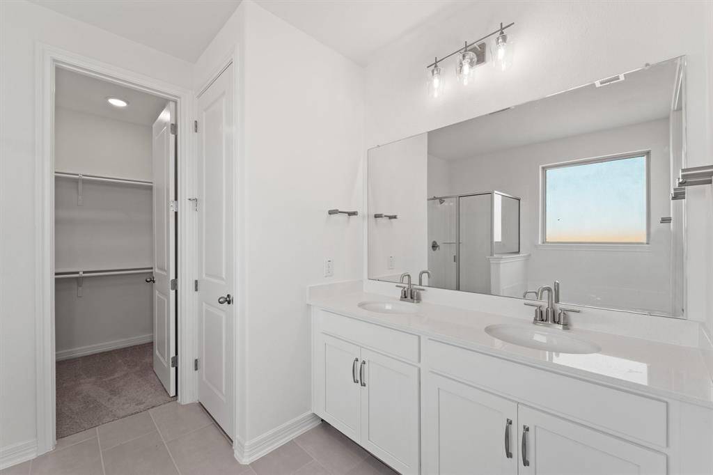 The en-suite bathroom offers a spa-like atmosphere with its elegant design, high end finishes, and tasteful lighting, creating a retreat within your own home.