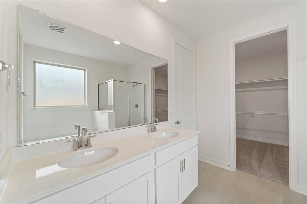 The en-suite bathroom offers a spa-like atmosphere with its elegant design, high end finishes, and tasteful lighting, creating a retreat within your own home.