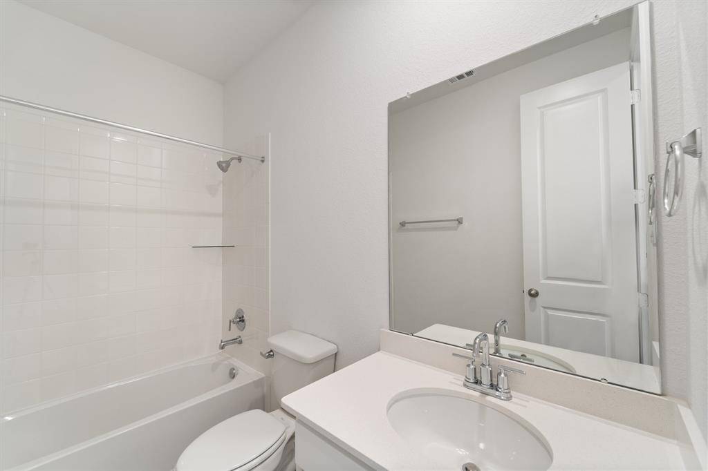 The secondary bath features tile flooring, white cabinetry and light countertops and a shower/tub combo. Perfect for accommodating any visiting family and friends.
