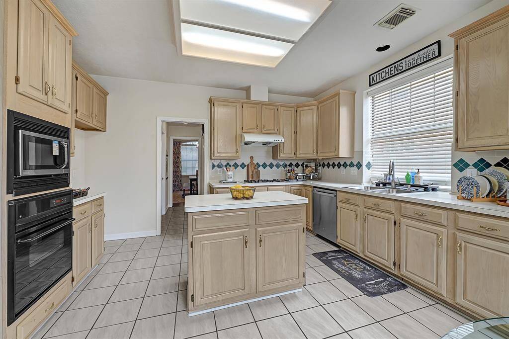 Well-appointed kitchen boasts a gas cooktop, built-in microwave and oven, and stainless steel dishwasher. The central island provides extra prep space and storage.