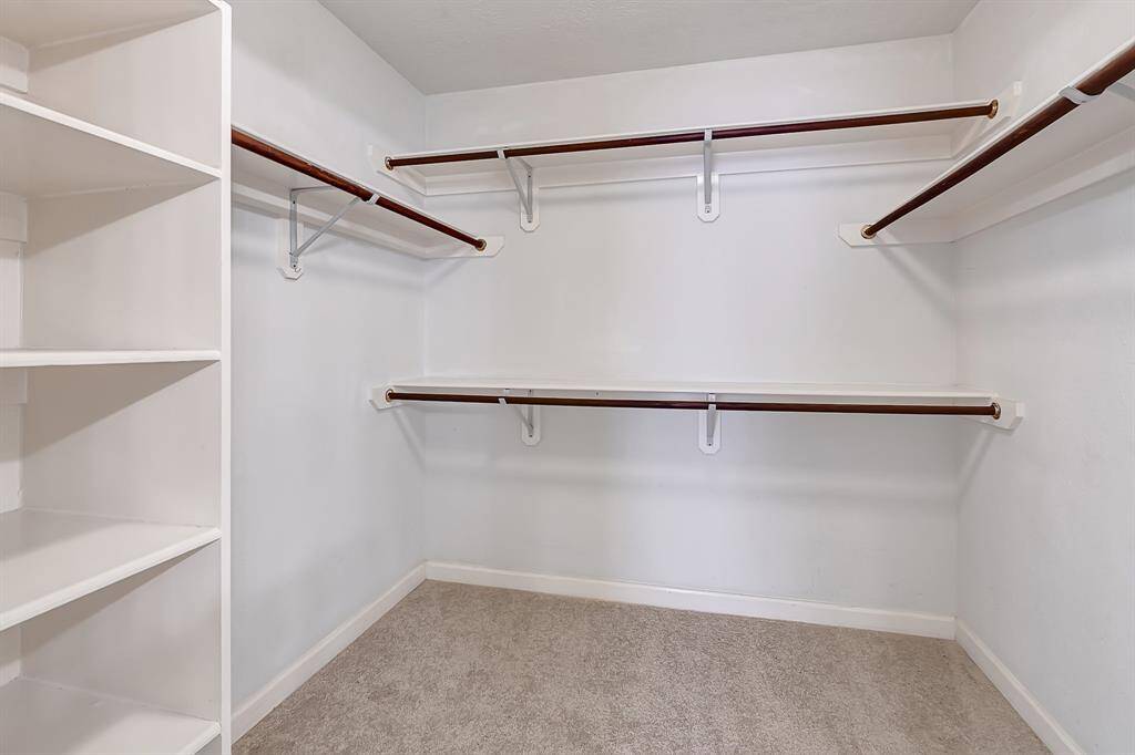 Generously sized walk-in closet with custom built-in shelving and ample hanging space. Designed to keep everything organized and easily accessible.