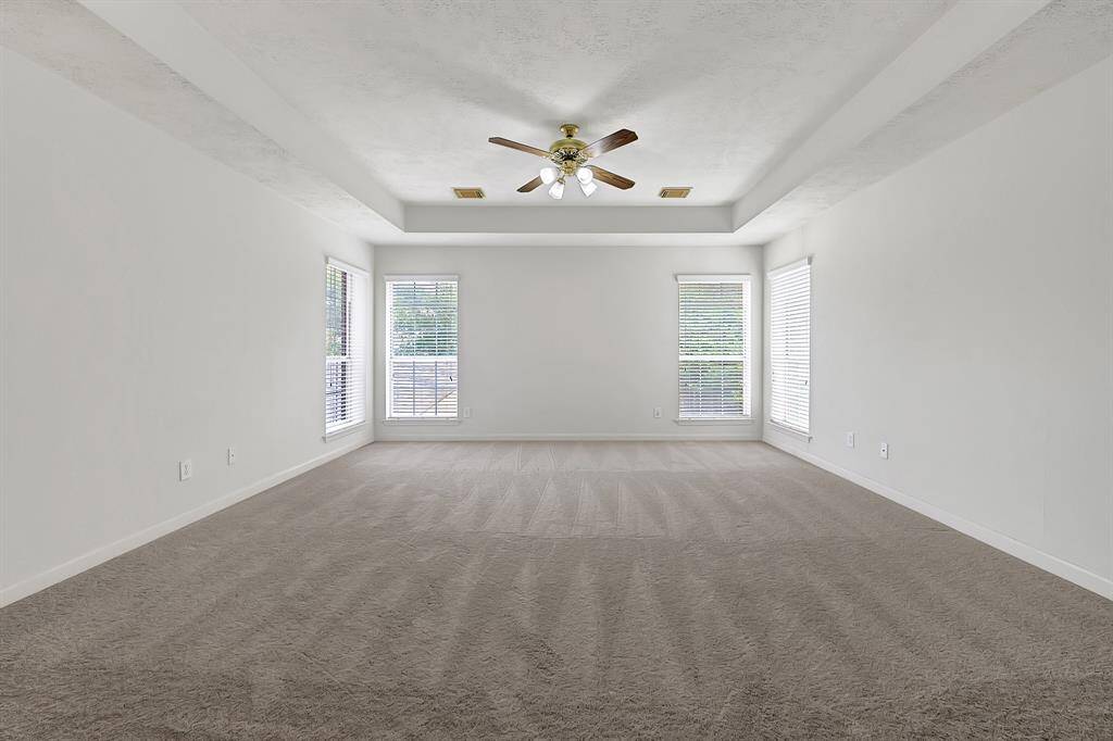 Expansive bonus room with fresh carpet, tray ceiling, and multiple windows for natural light. Ideal as a game room, media room, or additional living space.