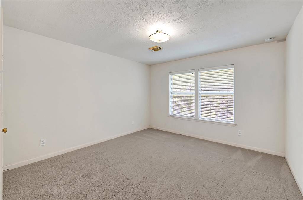 This secondary bedroom offers newly installed soft carpeting, double windows for natural light, and ample wall space for furnishings or art..
