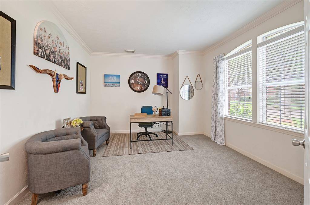 Bright and functional home office with large front-facing windows that let in natural light. Features newly installed plush carpet, crown molding, and enough space for work or reading.