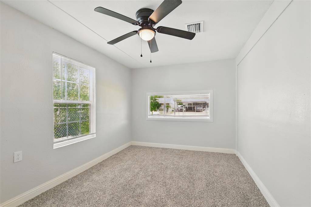 Comfortable bedroom with soft carpet, double windows for cross breeze, and ceiling fan for added comfort year-round.