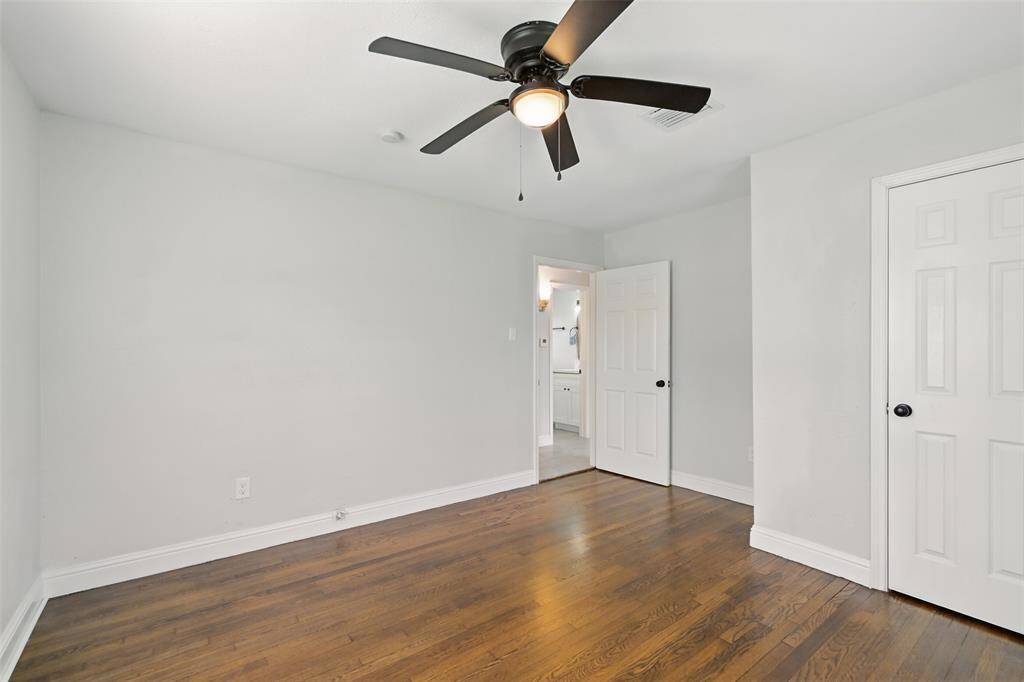Secondary bedroom with sleek ceiling fan, soft neutral tones, and a view into the home's main areas—perfect for a guest room or home office.