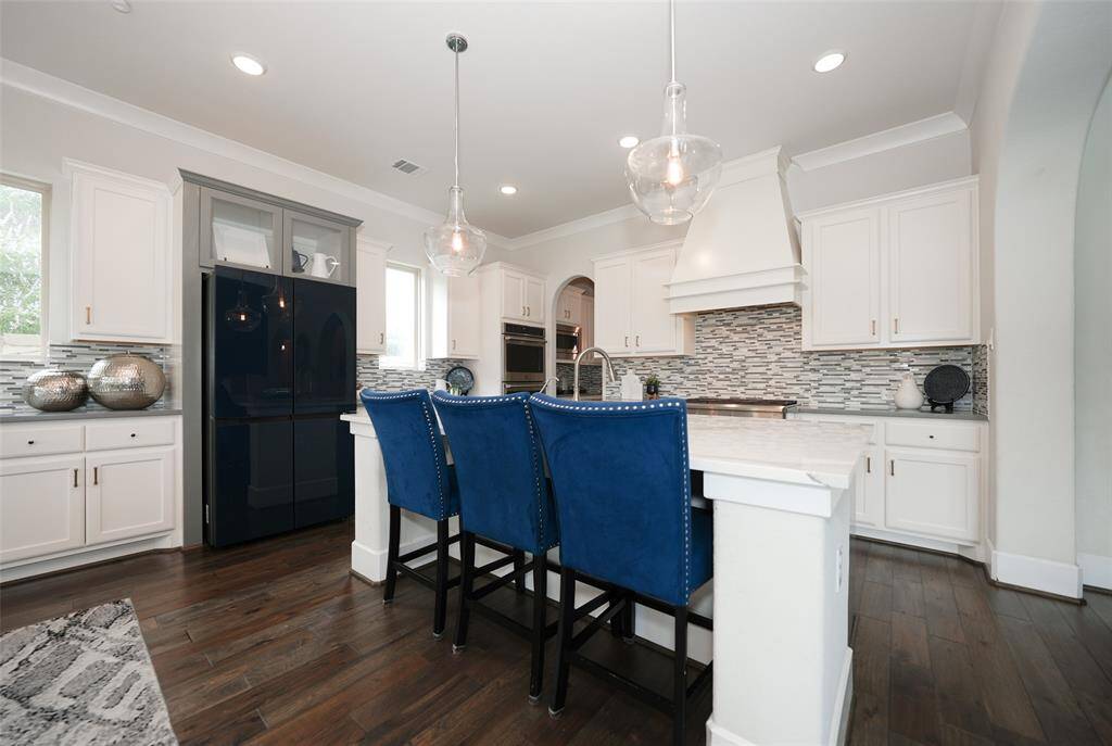 Elegant chef's kitchen with an island, ample counter space, and a six-burner gas stove with a stylish vent hood.