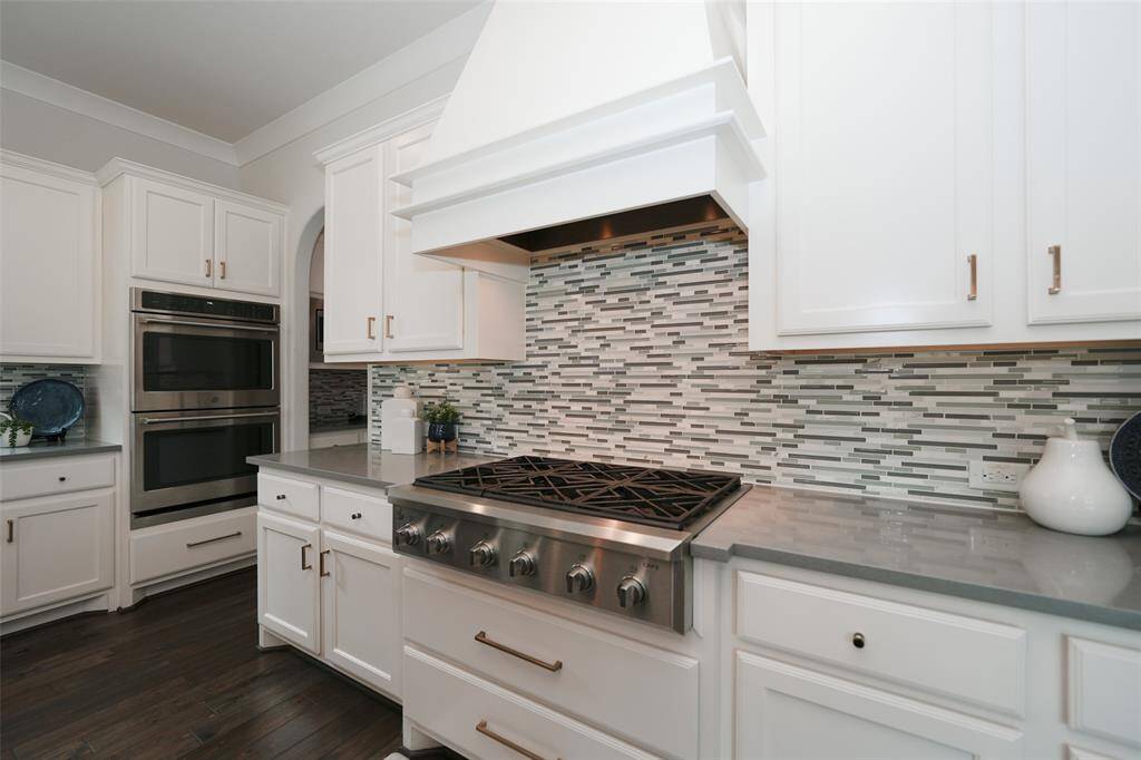 Experience culinary excellence with a six-burner cooktop, abundant counter space, and a stunning vent hood seamlessly integrated into the kitchen design.