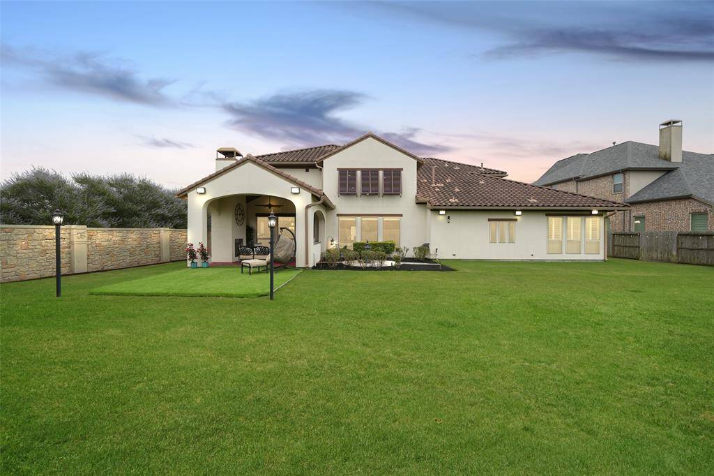 Expansive lot featuring a beautifully lit patio with twinkle lights, a fireplace, and an outdoor kitchen. Enjoy ample seating and extended concrete space for breezy evenings. Perfectly illuminated for memorable evening gatherings.