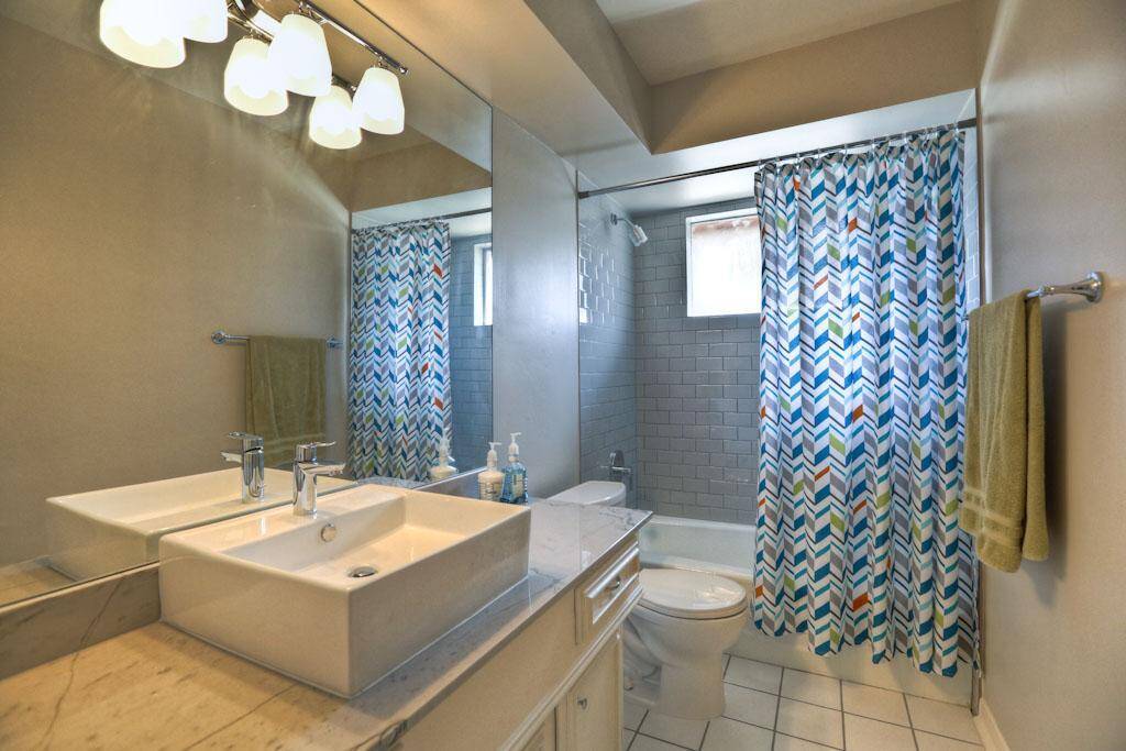 Hall bath also features stylish countertops, tile, sinks, plumbing and lighting fixtures.