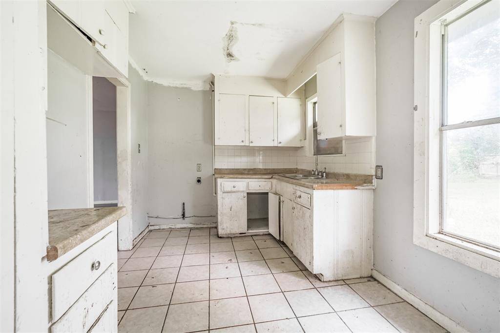 A spacious corner layout with upper cabinets and counter space—retain the L-shape or redesign into a galley or peninsula concept. Plenty of potential for adding bar seating or enhancing storage.