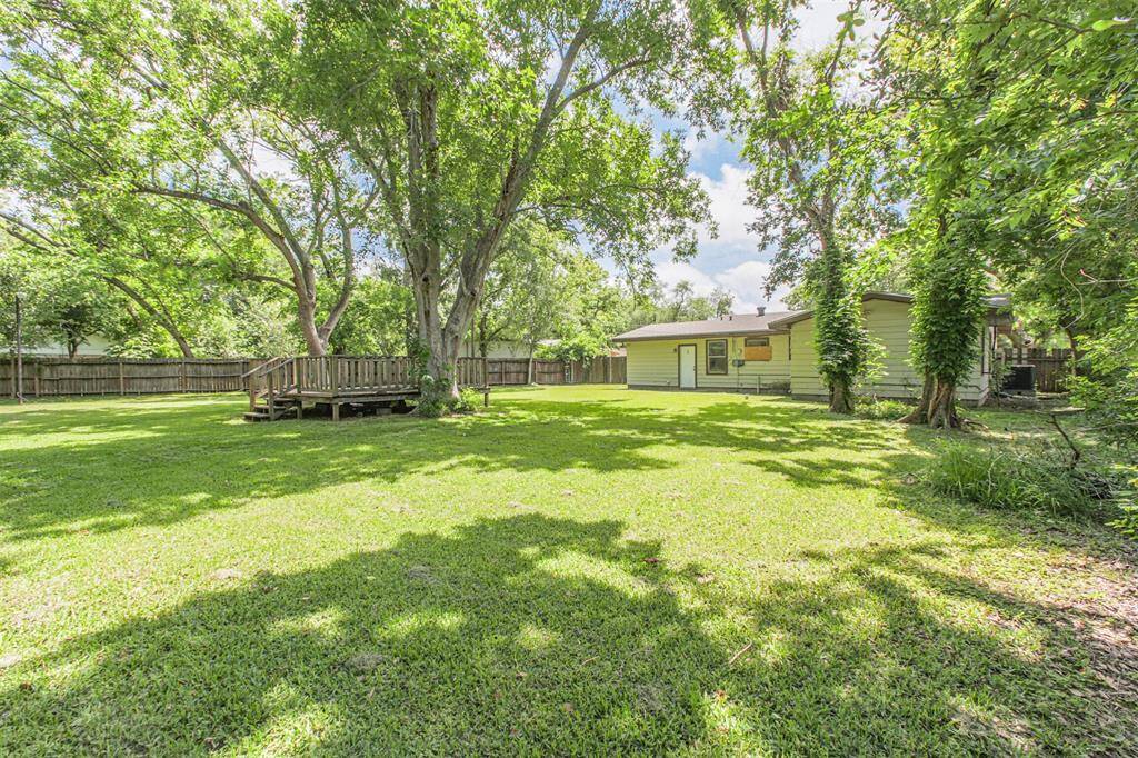 A unique wooden deck sits beneath shady trees—ready for revitalization or removal to open up even more yard space for expansion. With a little TLC, this shaded space could become the heart of the backyard, ideal for hosting gatherings or enjoying quiet moments surrounded by nature.