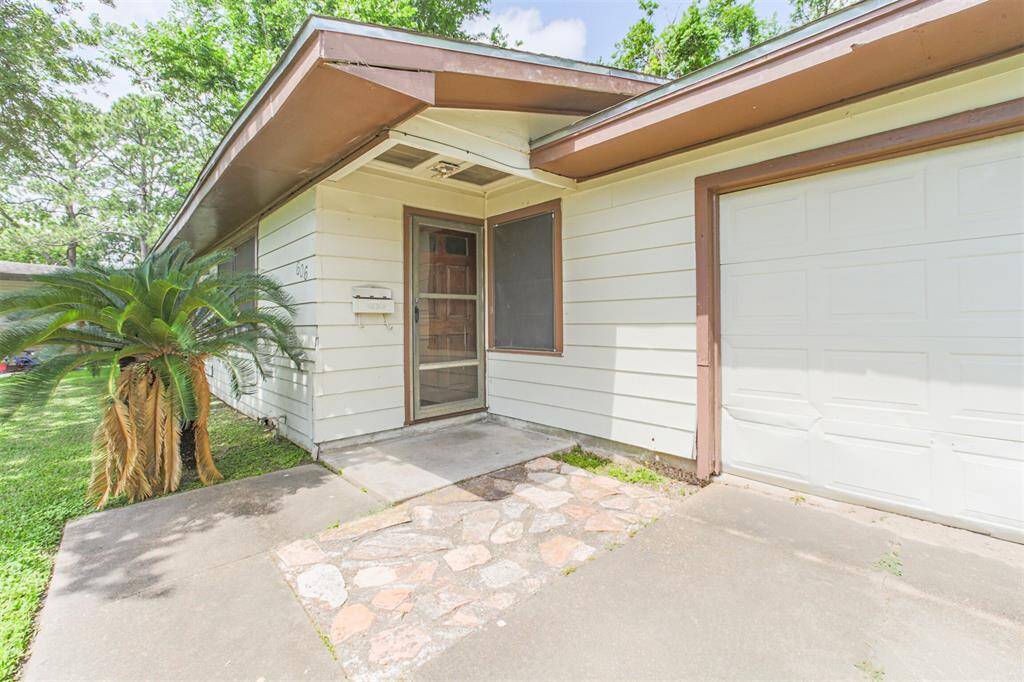 Charming entryway with covered porch and original details make for an ideal entry to welcome guests. The attached garage offers convenience and added value, while the stone path hints at character that can be enhanced with minimal upgrades. Great curb appeal potential on a quiet street near Galveston!