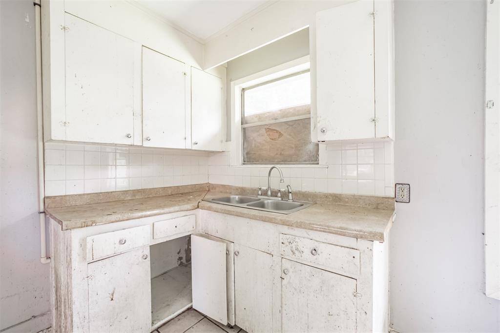This corner kitchen layout with double sink and full backsplash offers a strong layout foundation for a refresh or a full redesign that opens up to the main living space.