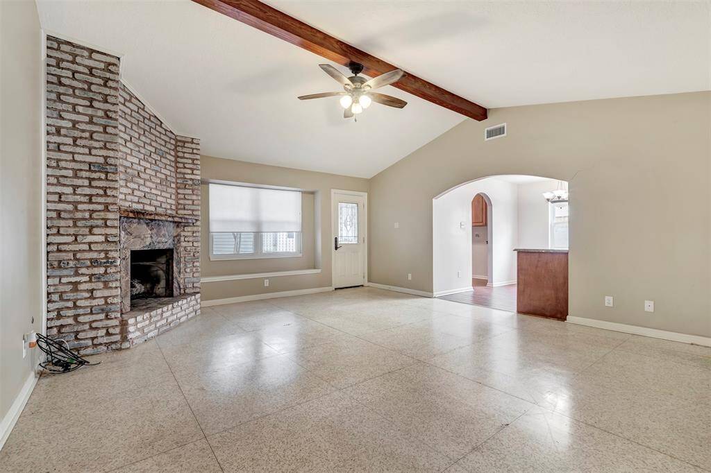 Cozy family room featuring a sleek gas fireplace and elegant terrazzo flooring, with an arched doorway connecting to the kitchen.