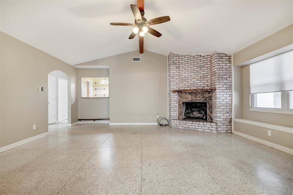 Cozy family room featuring a gas fireplace, an adjacent wet bar with bar top access, and elegant terrazzo flooring.