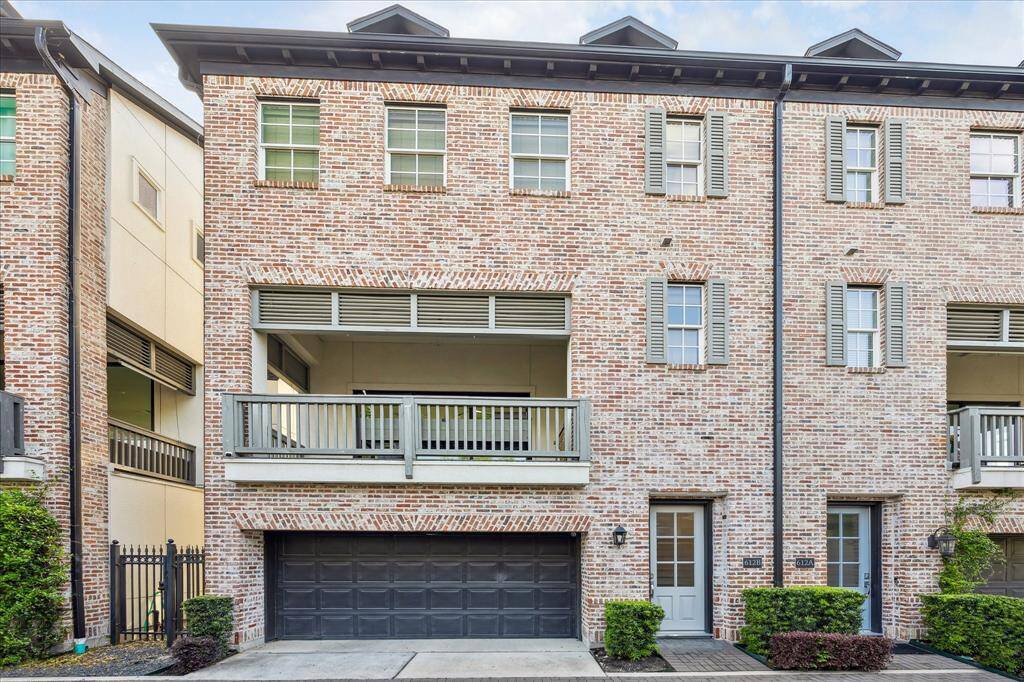 Features brick exterior and a two-car garage. Fabulous covered balcony on the second floor, accented with shutters and greenery on either side.