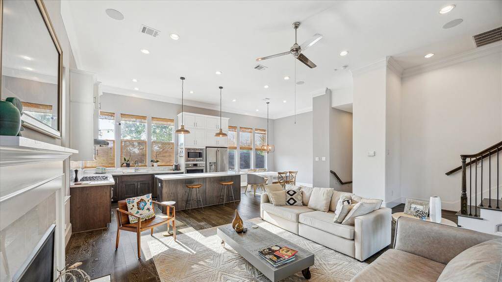 This open-concept living area features a spacious kitchen with a large island, modern appliances, and ample natural light from numerous windows. The room includes a comfortable seating area, high ceilings, and elegant finishes, creating a bright and inviting space perfect for entertaining.