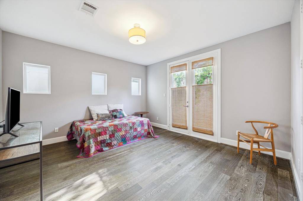 Bright, spacious first floor bedroom with modern gray walls, hardwood flooring, and ample natural light from large windows.