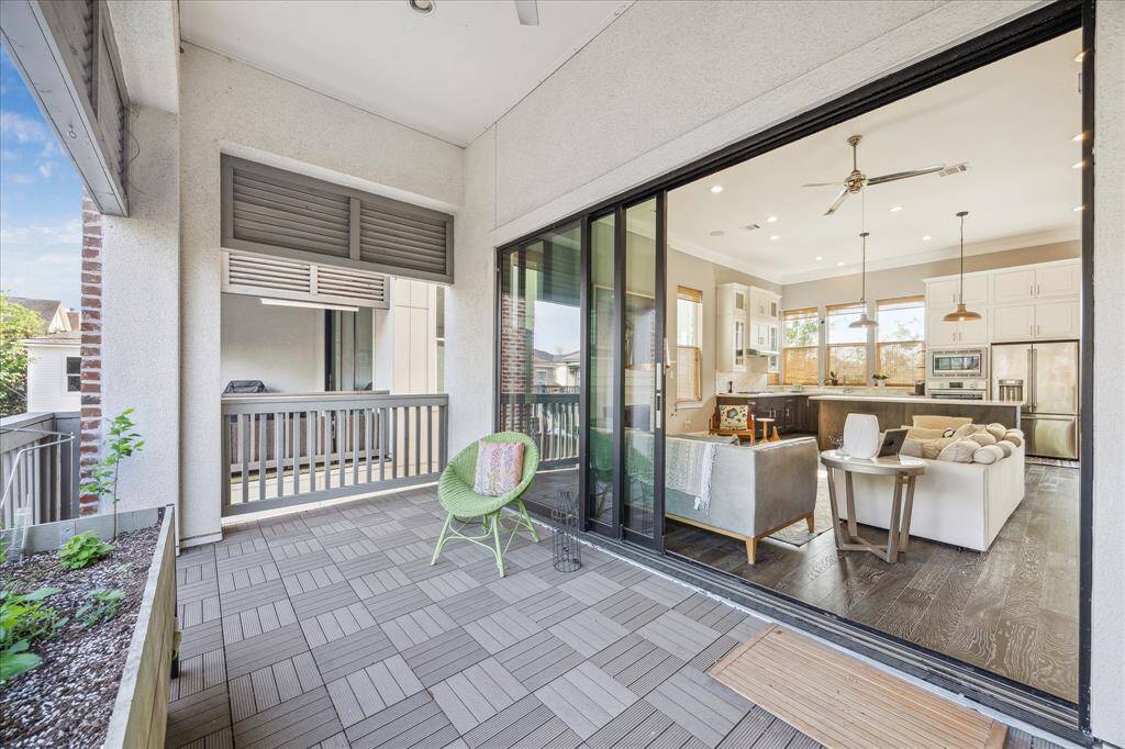 This photo showcases a bright, open-concept living area with large sliding glass doors leading to a spacious balcony. The interior features modern finishes, a cozy seating area, and a contemporary kitchen with ample natural light.