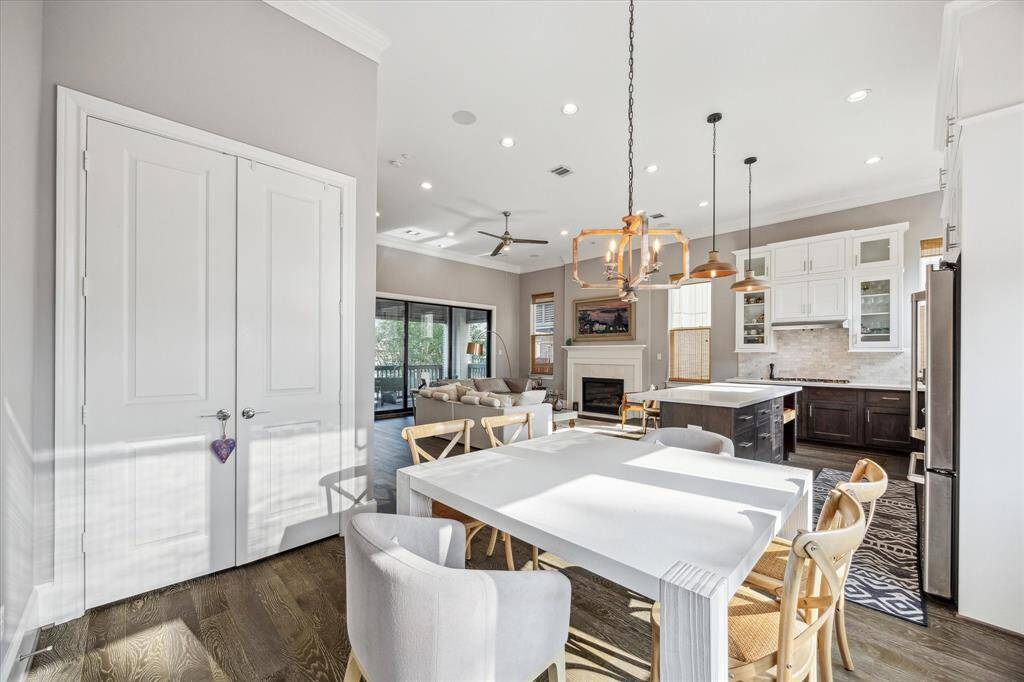 Open-concept living space with a gorgeous kitchen, dining area, and cozy living room. It features high ceilings, stylish lighting, and a fireplace, creating a welcoming atmosphere.