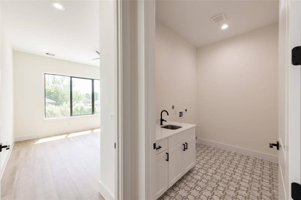 Spacious upstairs utility room featuring elegant tile flooring and a built-in sink, perfectly located between all bedrooms for added convenience.