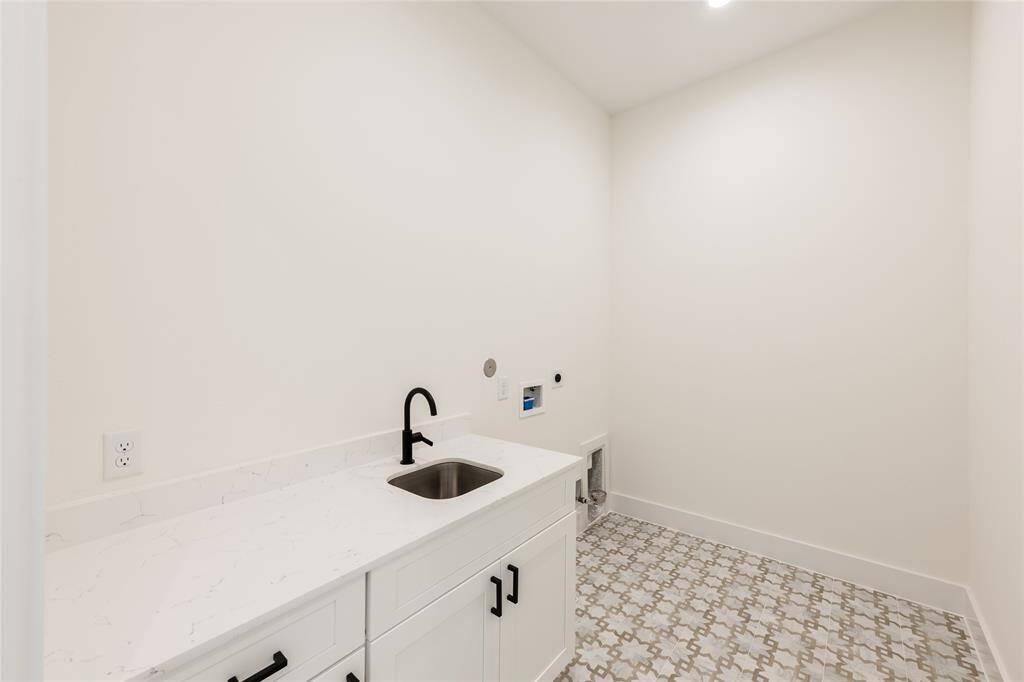 Spacious upstairs utility room featuring elegant tile flooring and a built-in sink, perfectly located between all bedrooms for added convenience.