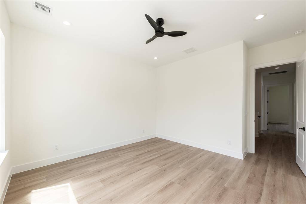 Another view of the sunlit primary bedroom, offering a glimpse of the generous walk-in closet—perfect for organized and stylish living