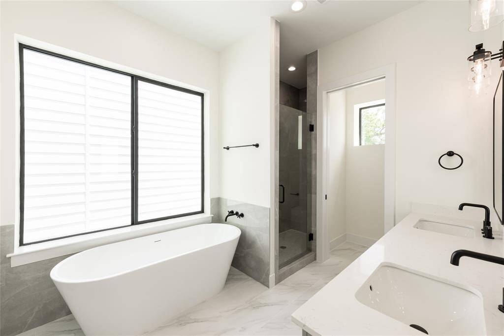 Luxurious primary bathroom featuring a freestanding soaking tub, a sleek standing shower, and double sinks—offering both style and functionality in a serene, spa-like retreat.