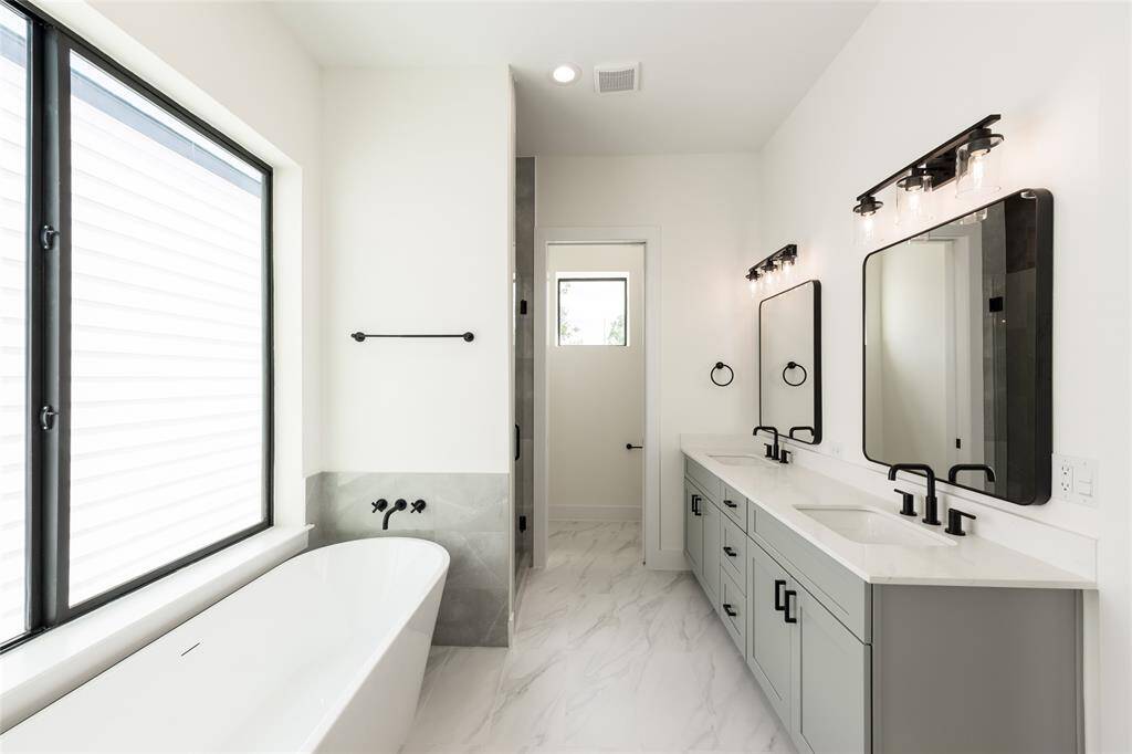 Luxurious primary bathroom featuring a freestanding soaking tub, a sleek standing shower, and double sinks—offering both style and functionality in a serene, spa-like retreat.